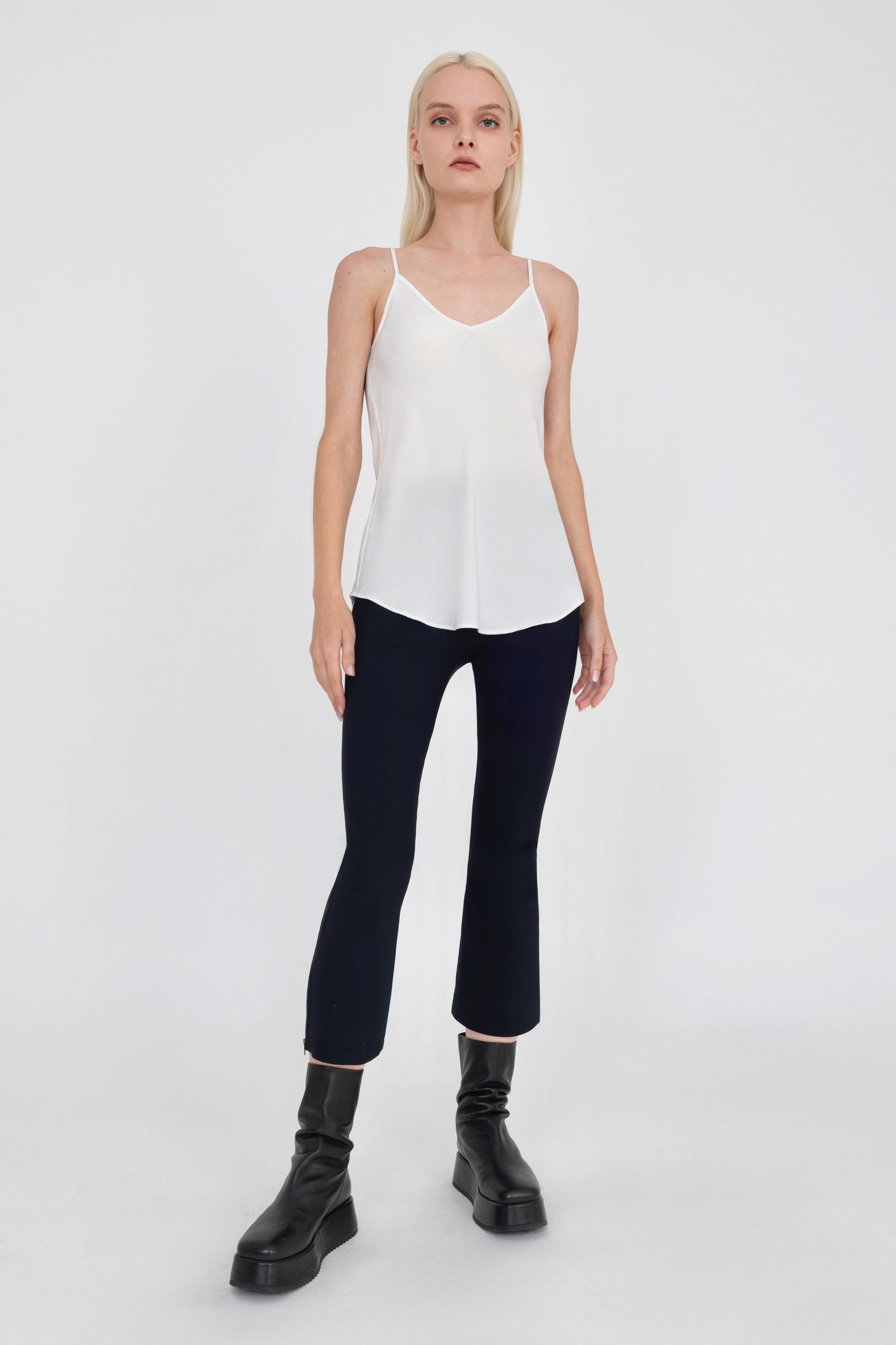 Woman wearing white top and black pants on a white background