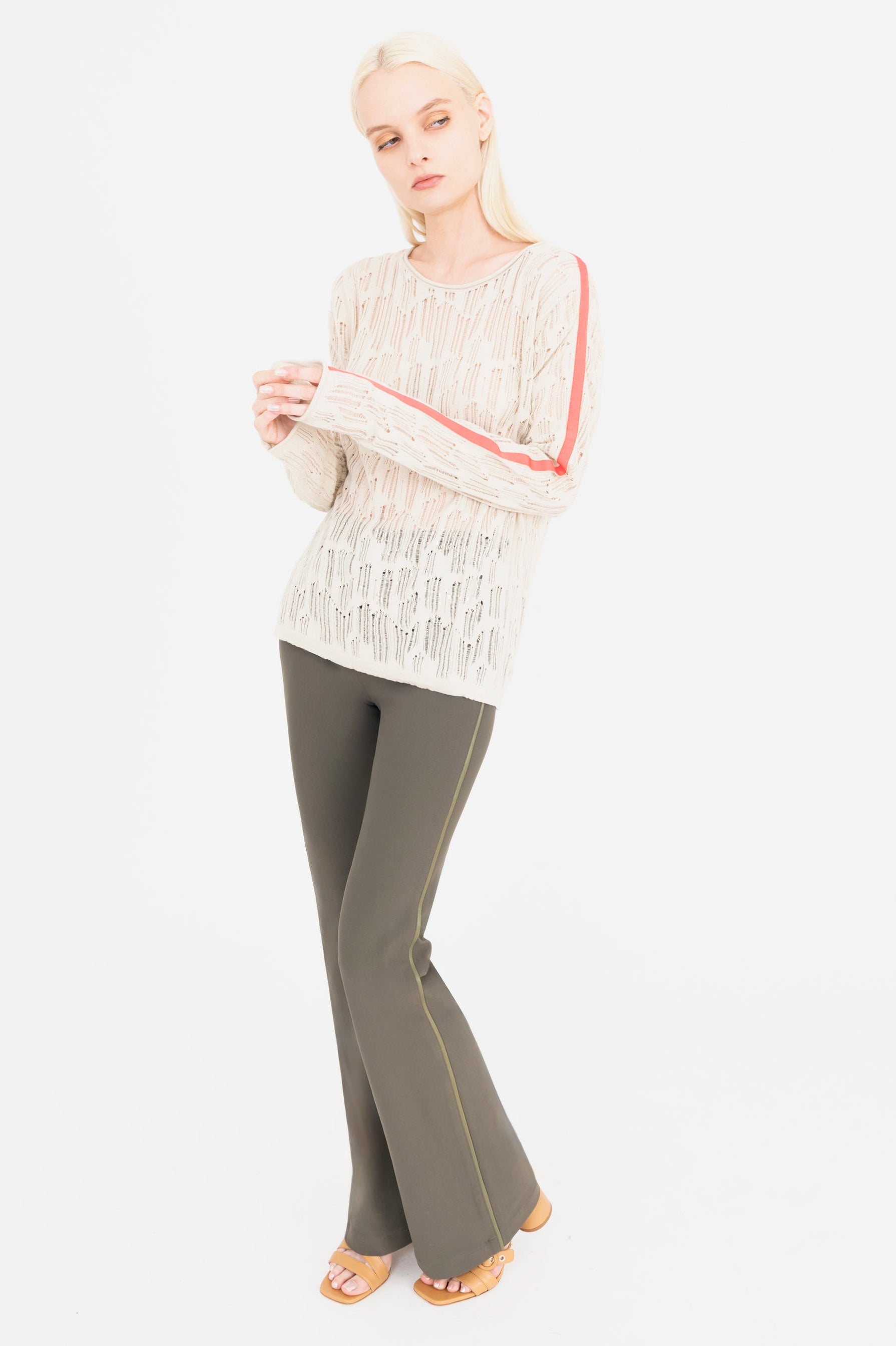 Woman wearing a beige sweater and olive green pants on a white background