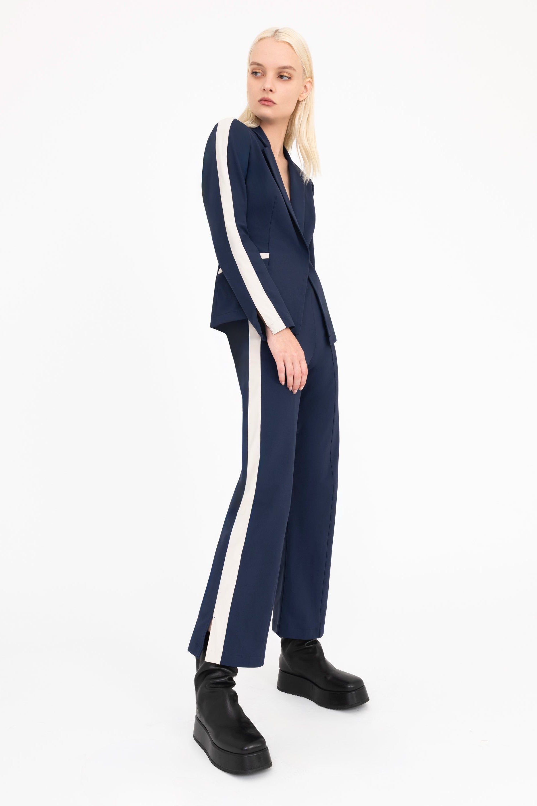 Woman wearing a navy suit with beige side stripe on a white background