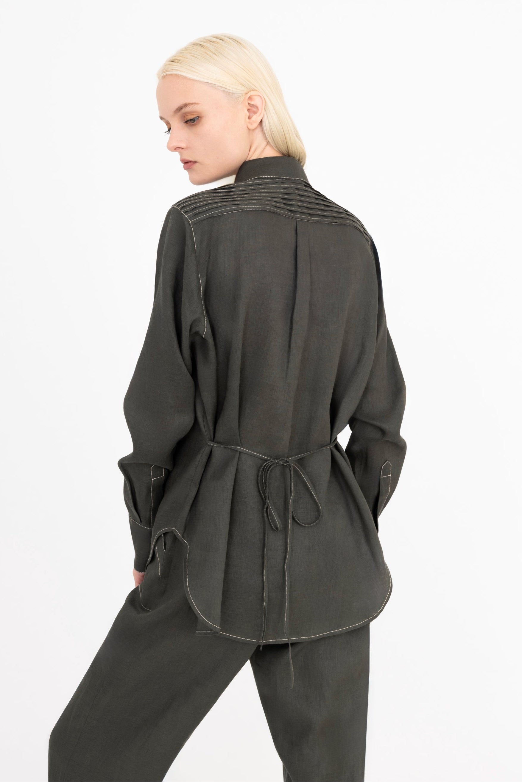 Woman wearing a pine green shirt and pants on a white background