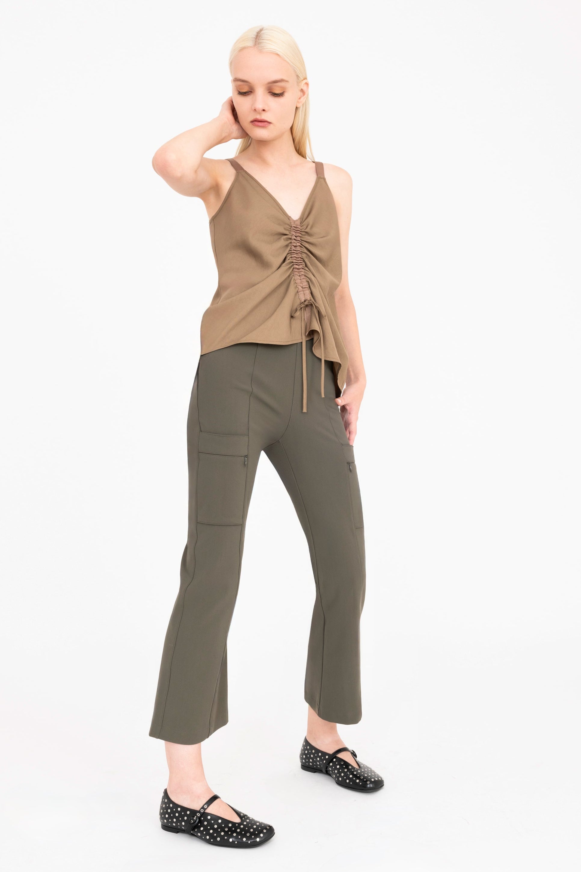 Woman wearing a brown top and green pants on a white background