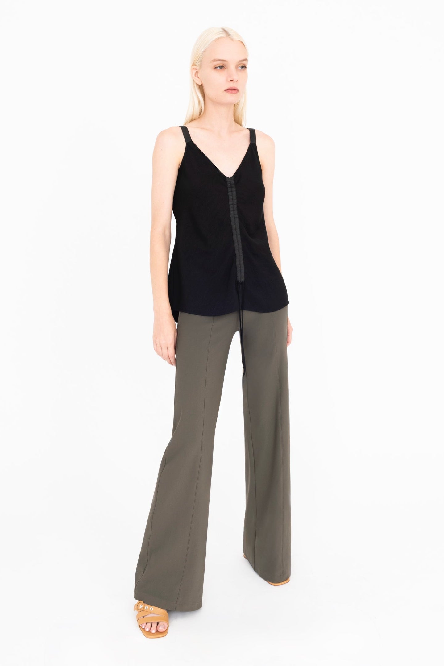 Woman wearing black top and green pants on a white background