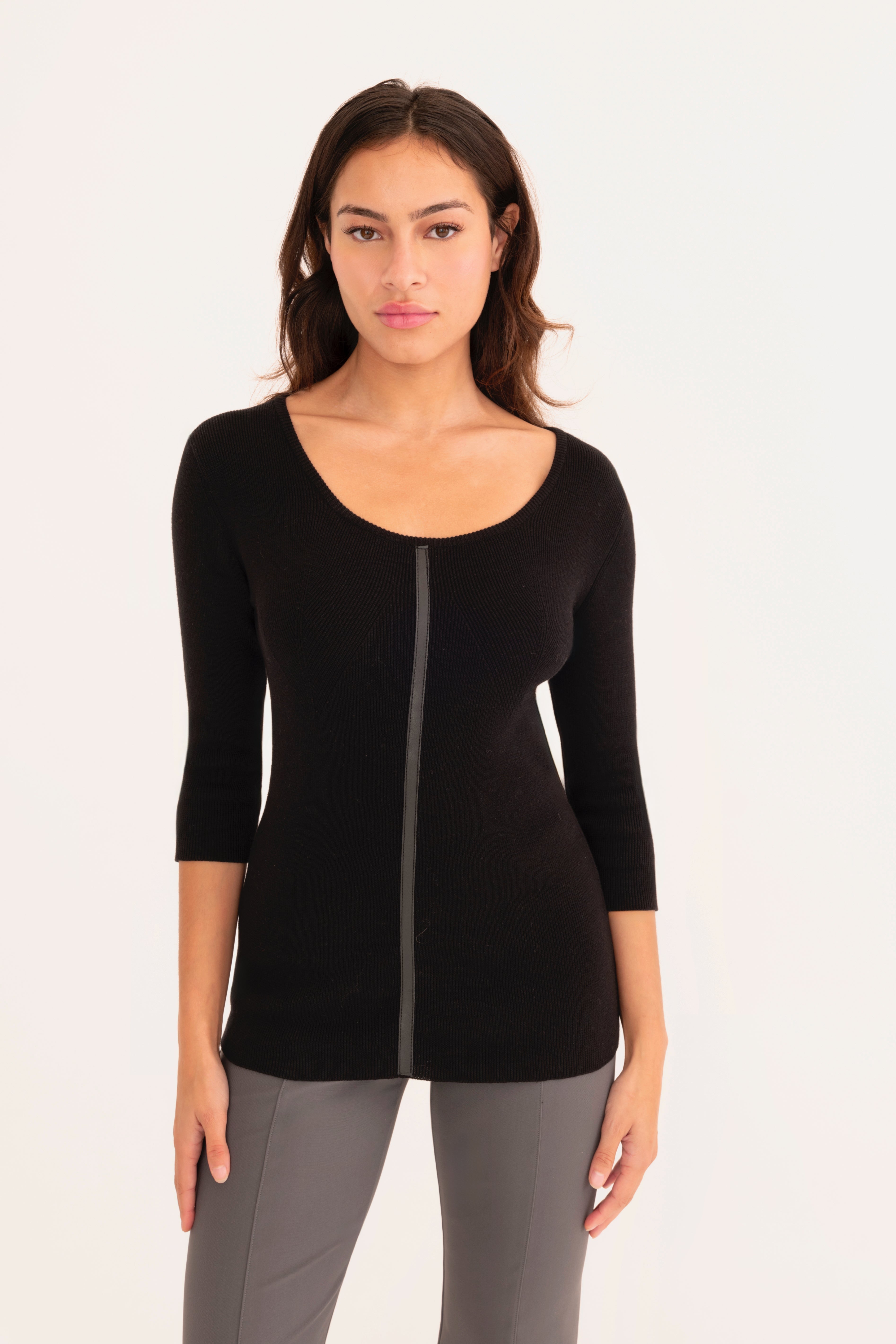 Front view of woman wearing a black top and gray pants on a white background