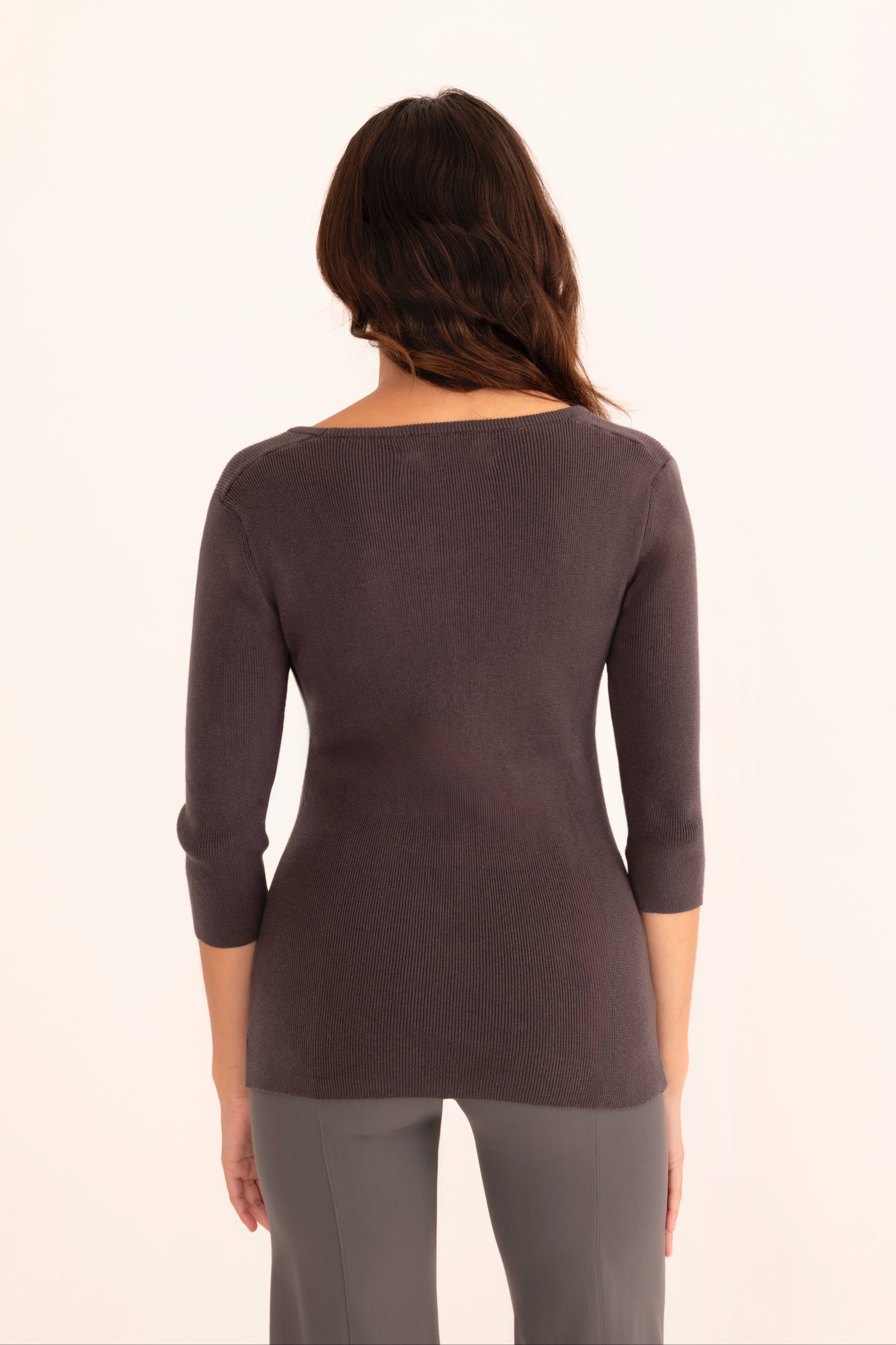 Back view of woman wearing a gray top and pants on a white background
