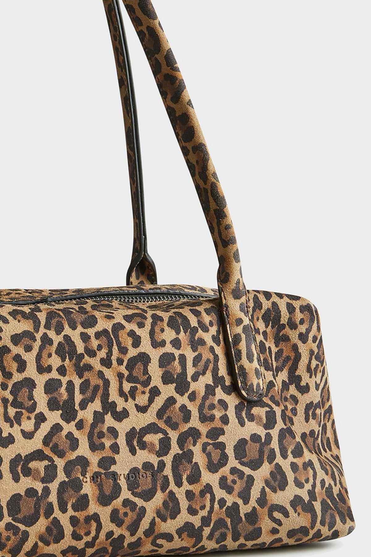 A close-up of a leopard print suede bag shown against a light gray background.