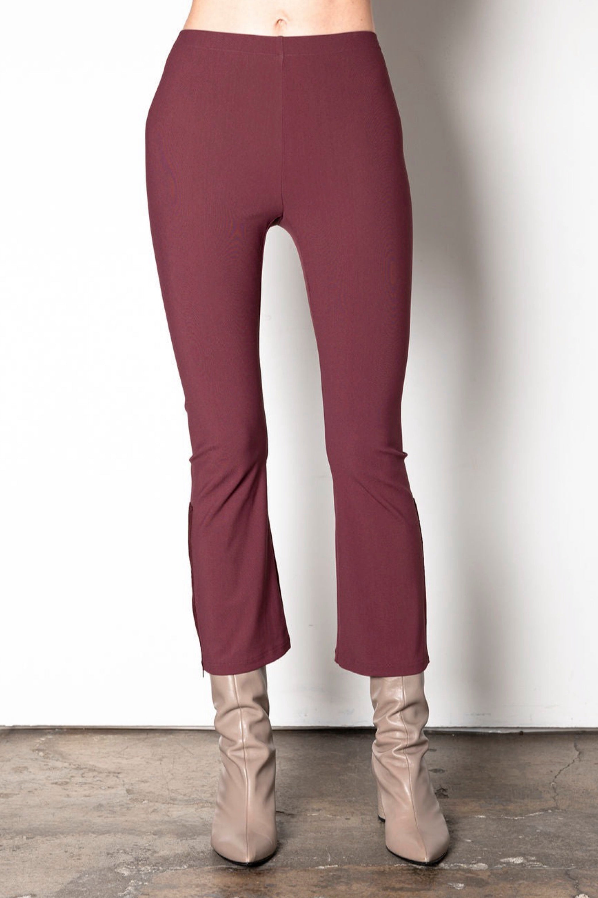 Maroon pants worn with beige boots on a plain background
