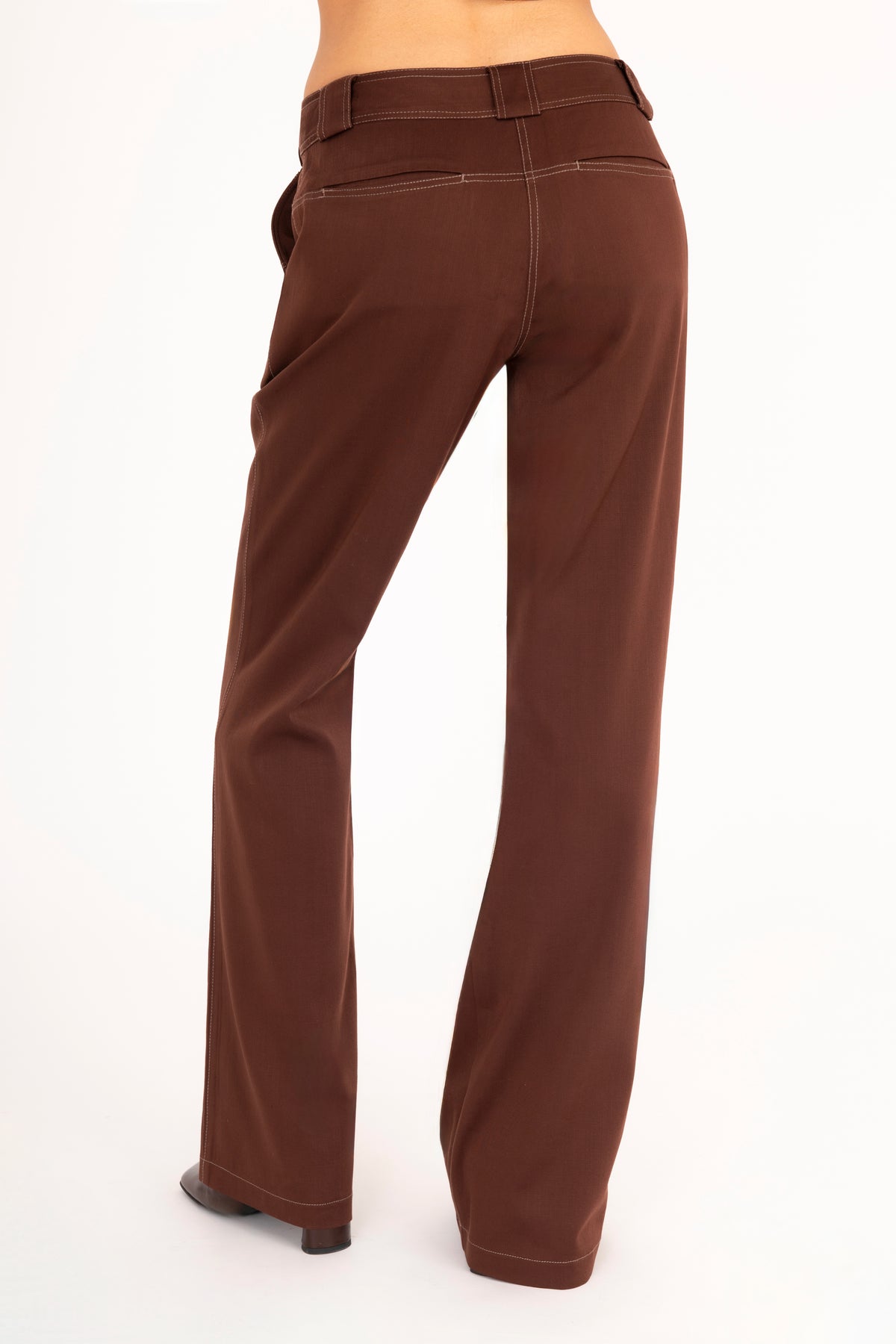 A woman shown from the back wearing brown wide-leg pants against a plain white studio background.