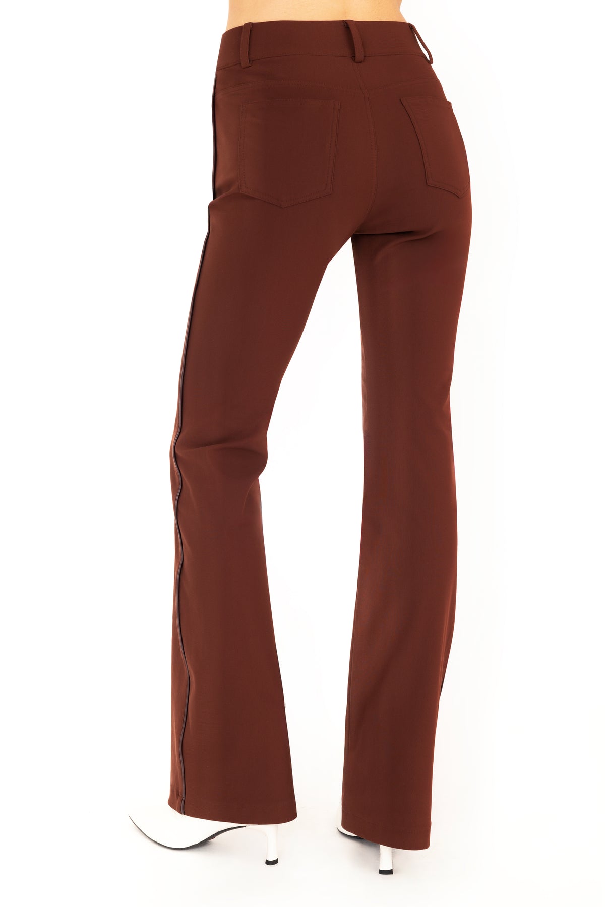 A pair of dark brown flare jean pants shown on a model from the waist down, paired with white pointed-toe boots against a plain white background.