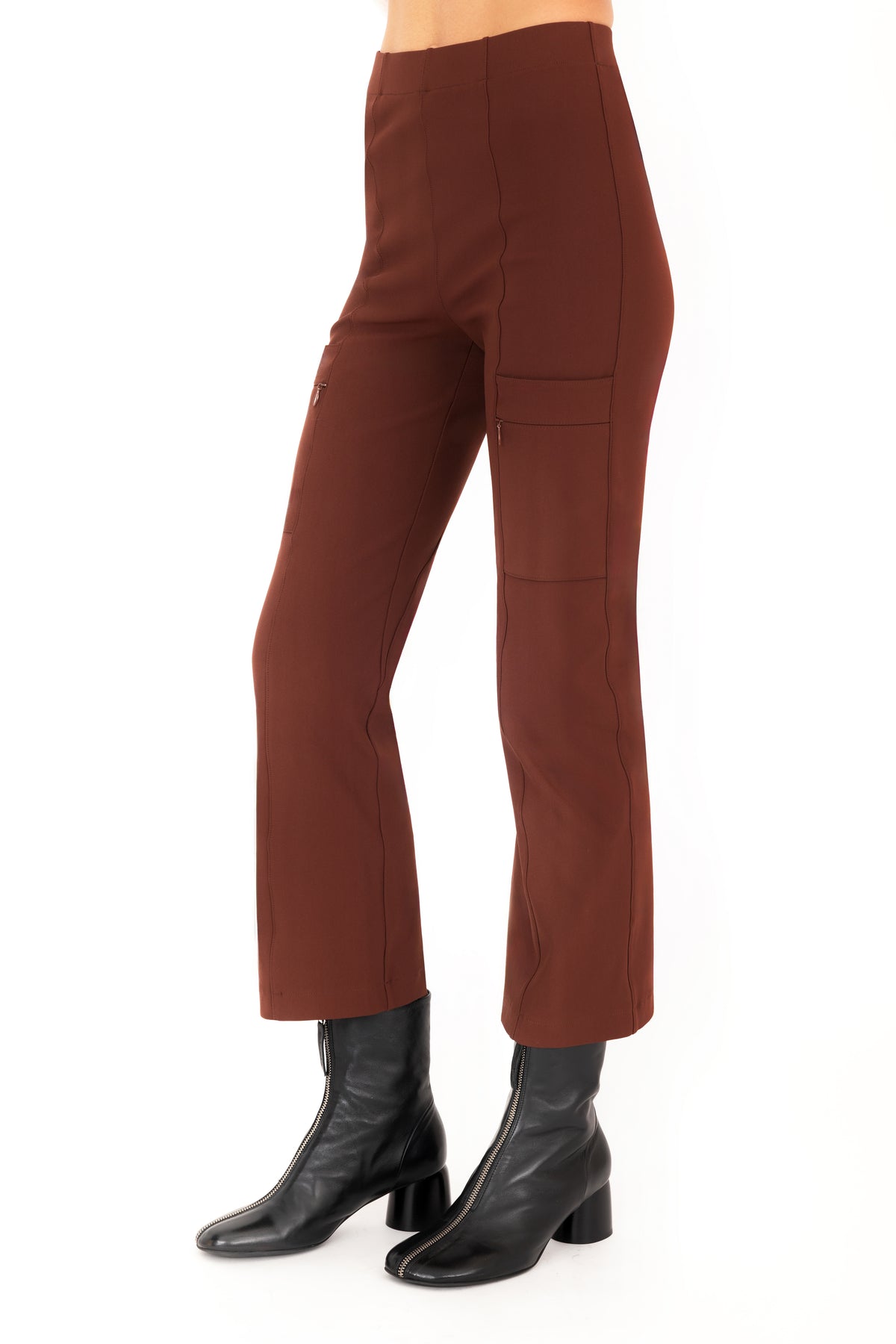 A model wearing brown cropped pants with side zip pockets and black ankle boots, shown from the waist down on a plain white studio background.
