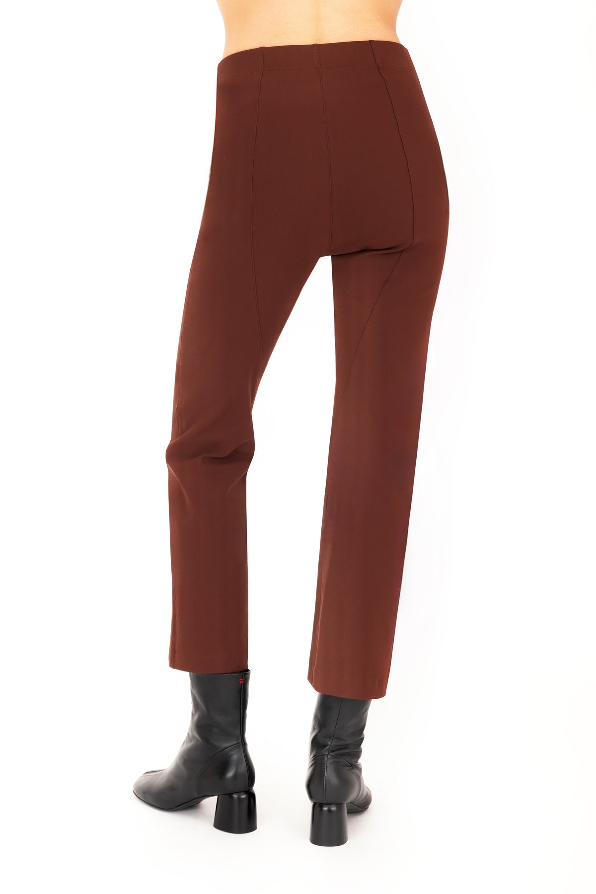 A model shown from the back wearing brown cropped pants with side zip pockets and black ankle boots, shown from the waist down on a plain white studio background.
