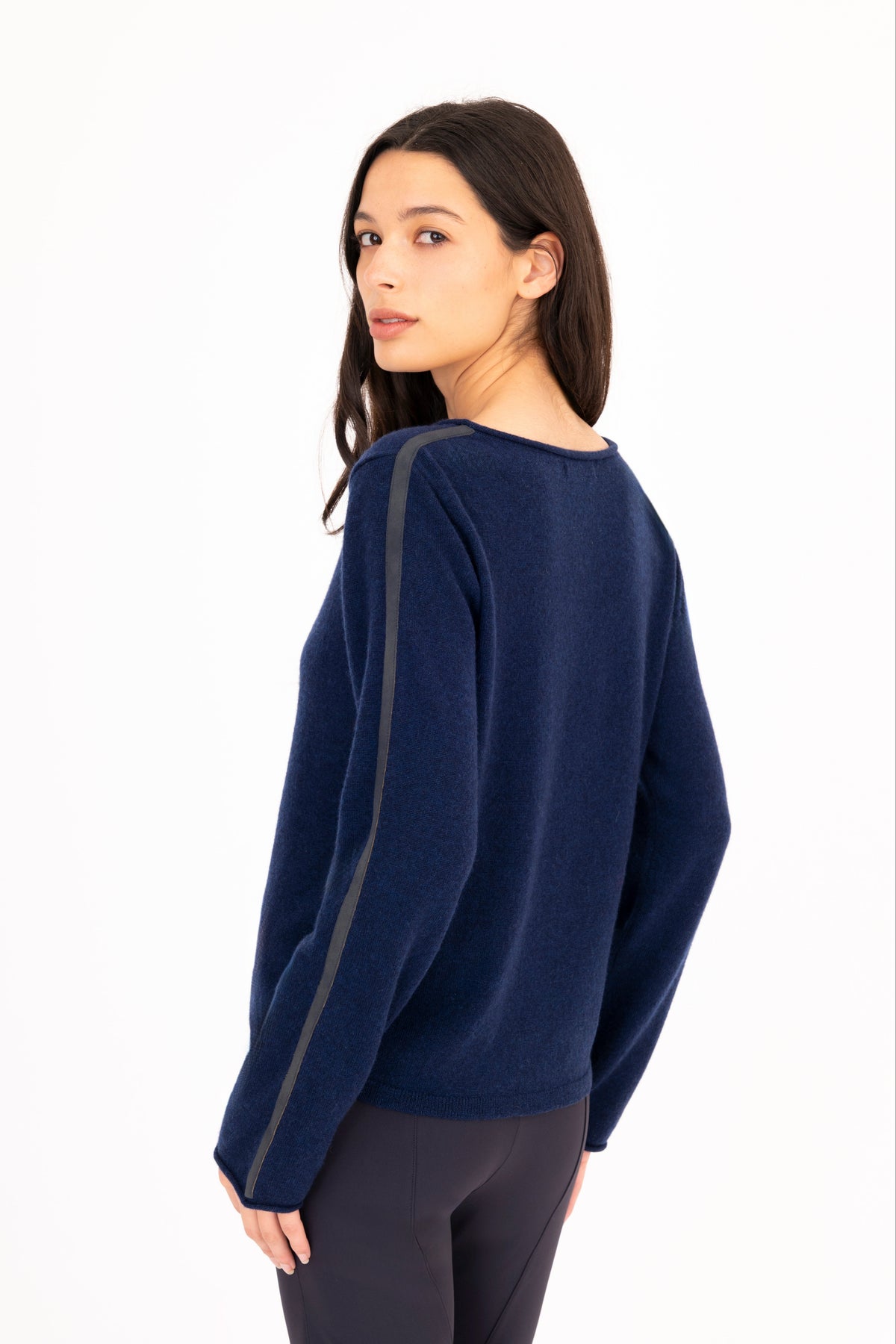 A woman modeling a navy blue long-sleeve knit sweater, paired with navy blue pants, against a plain white studio background.
