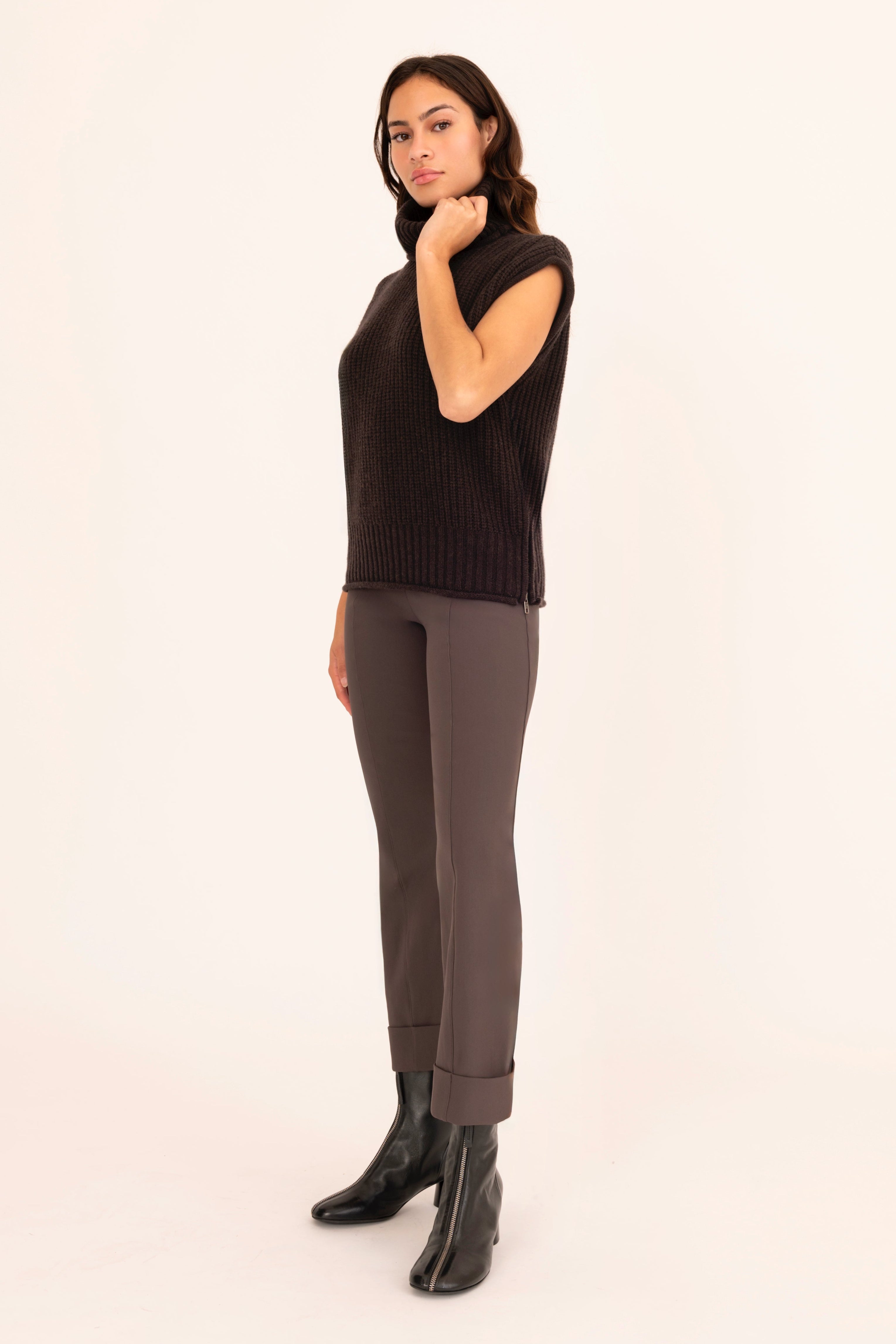 Woman wearing a brown sleeveless top and pants on a beige background