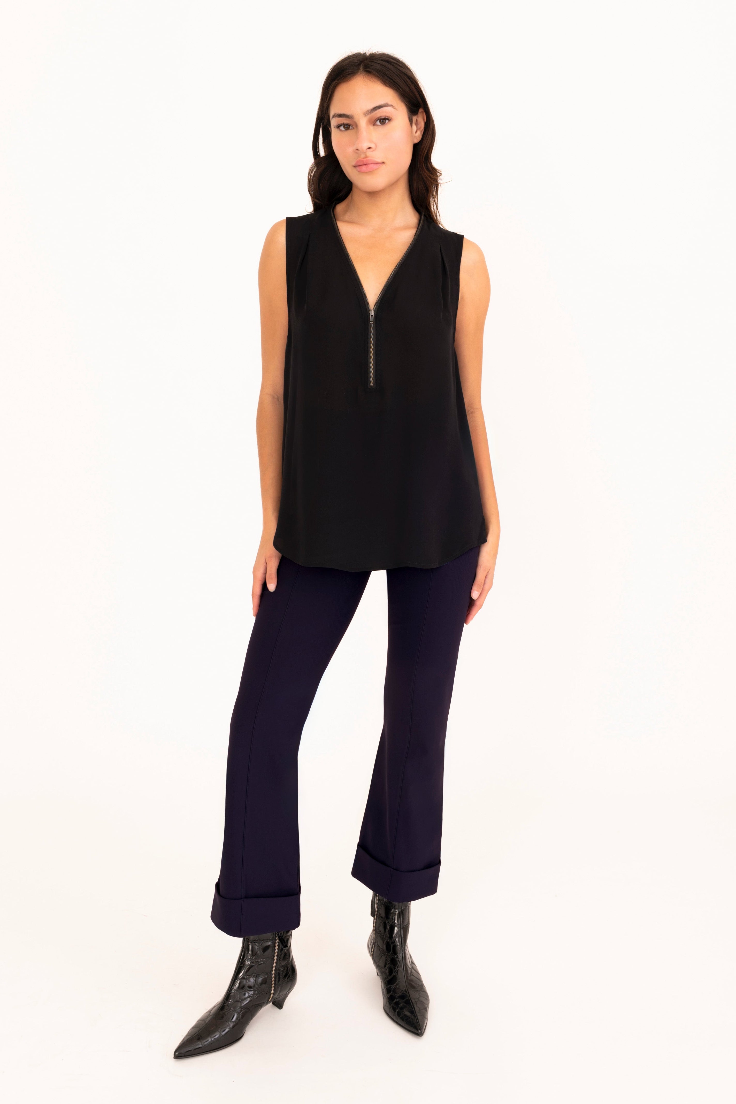 Woman wearing a black sleeveless top and dark blue pants on a white background