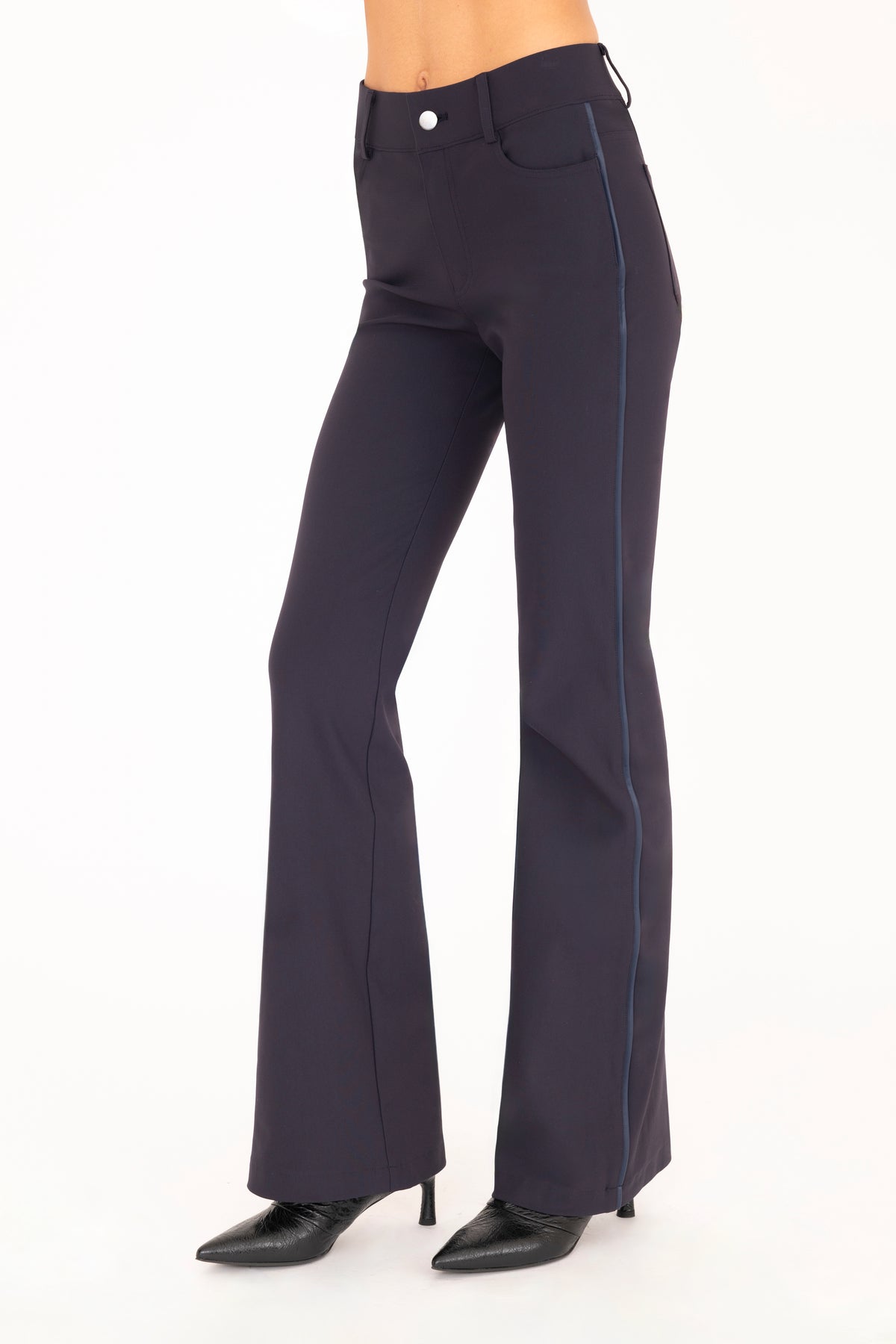 A pair of dark blue flare jean pants shown on a model from the waist down, paired with black pointed-toe boots against a plain white background.