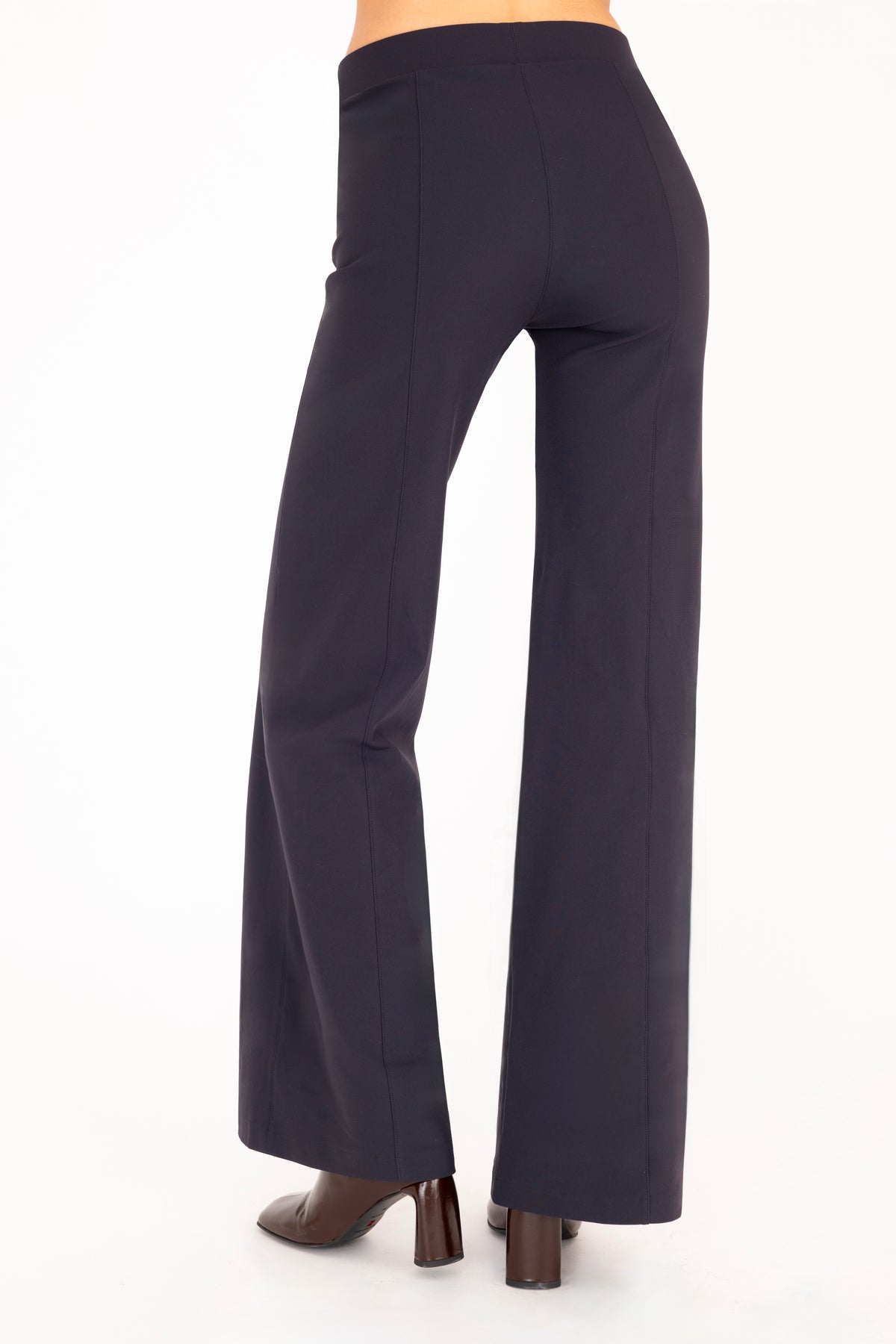 A model shown from the back wearing high-waisted, wide-leg navy blue pants with dark brown boots, shown from the waist down against a plain white background.