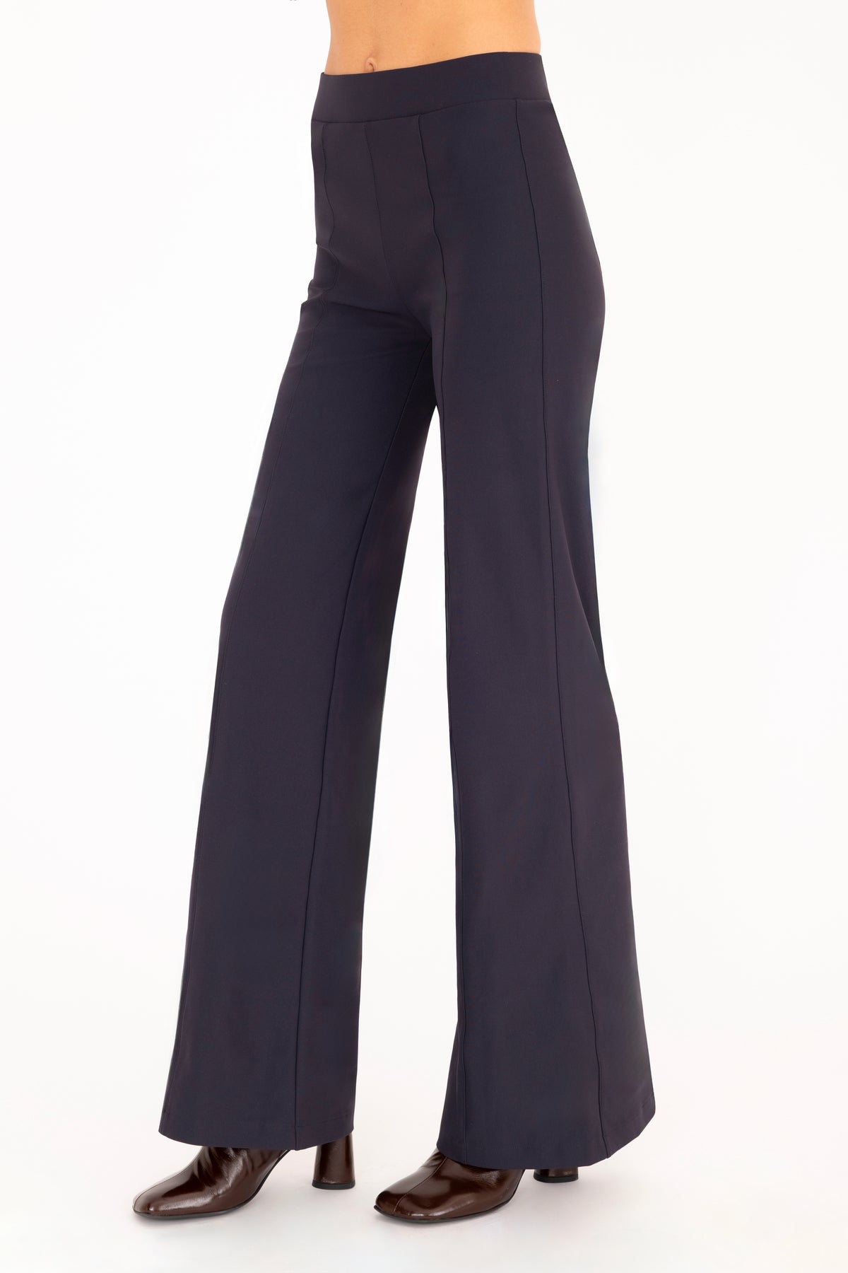 A model wearing high-waisted, wide-leg navy blue pants with dark brown boots, shown from the waist down against a plain white background.