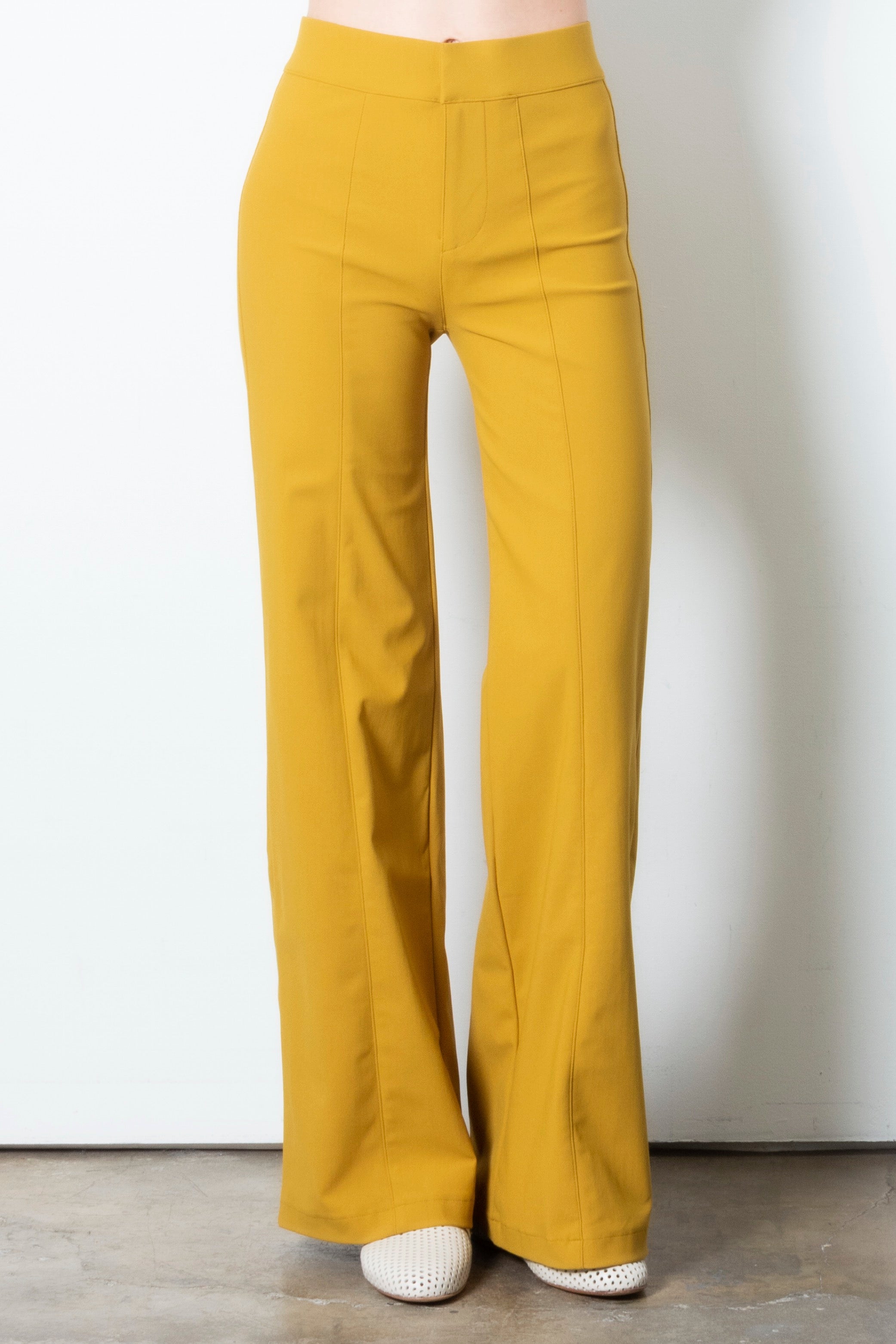 Mustard yellow wide leg pants on a plain background