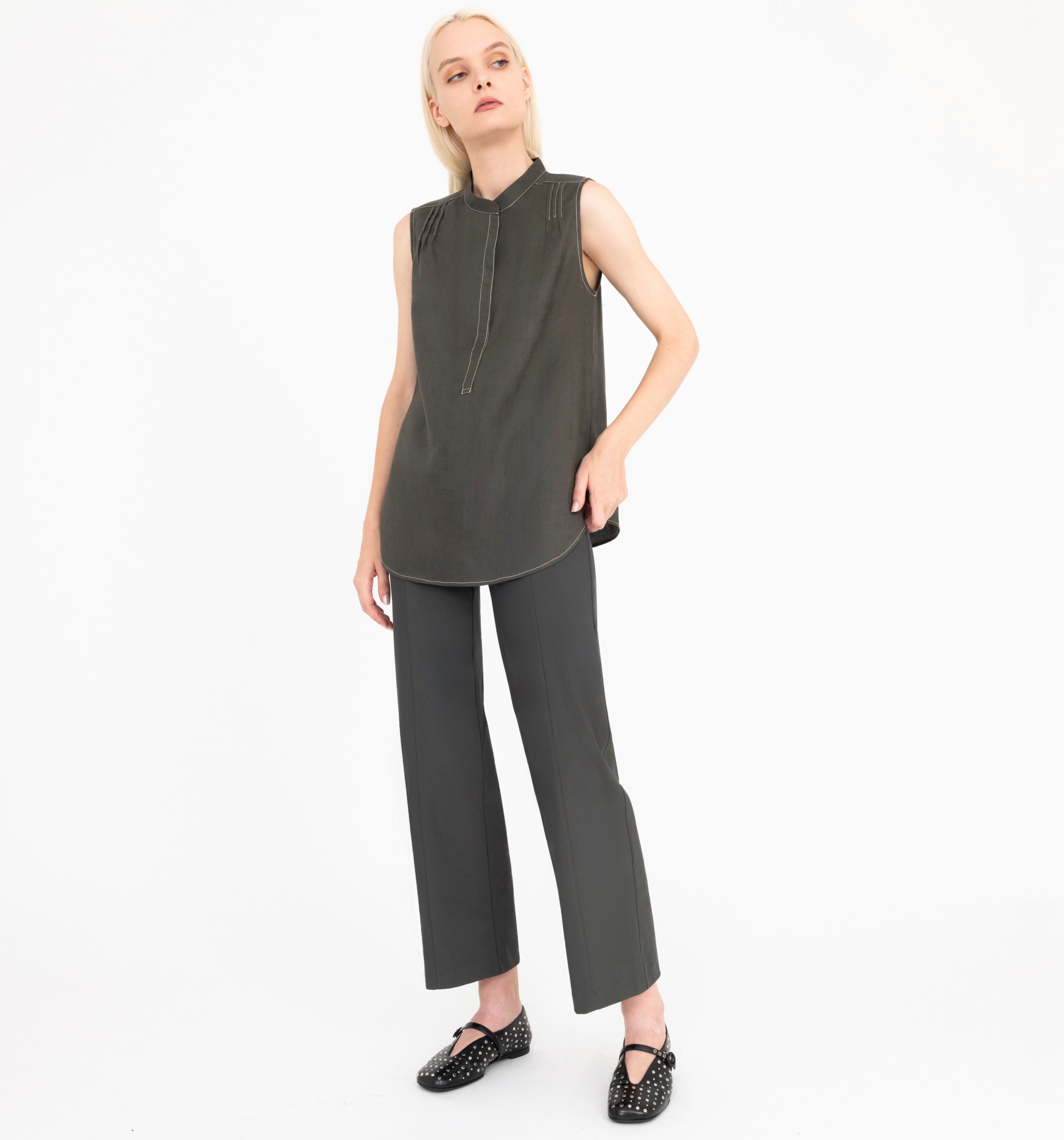 Woman wearing a sleeveless green top and pants on a white background