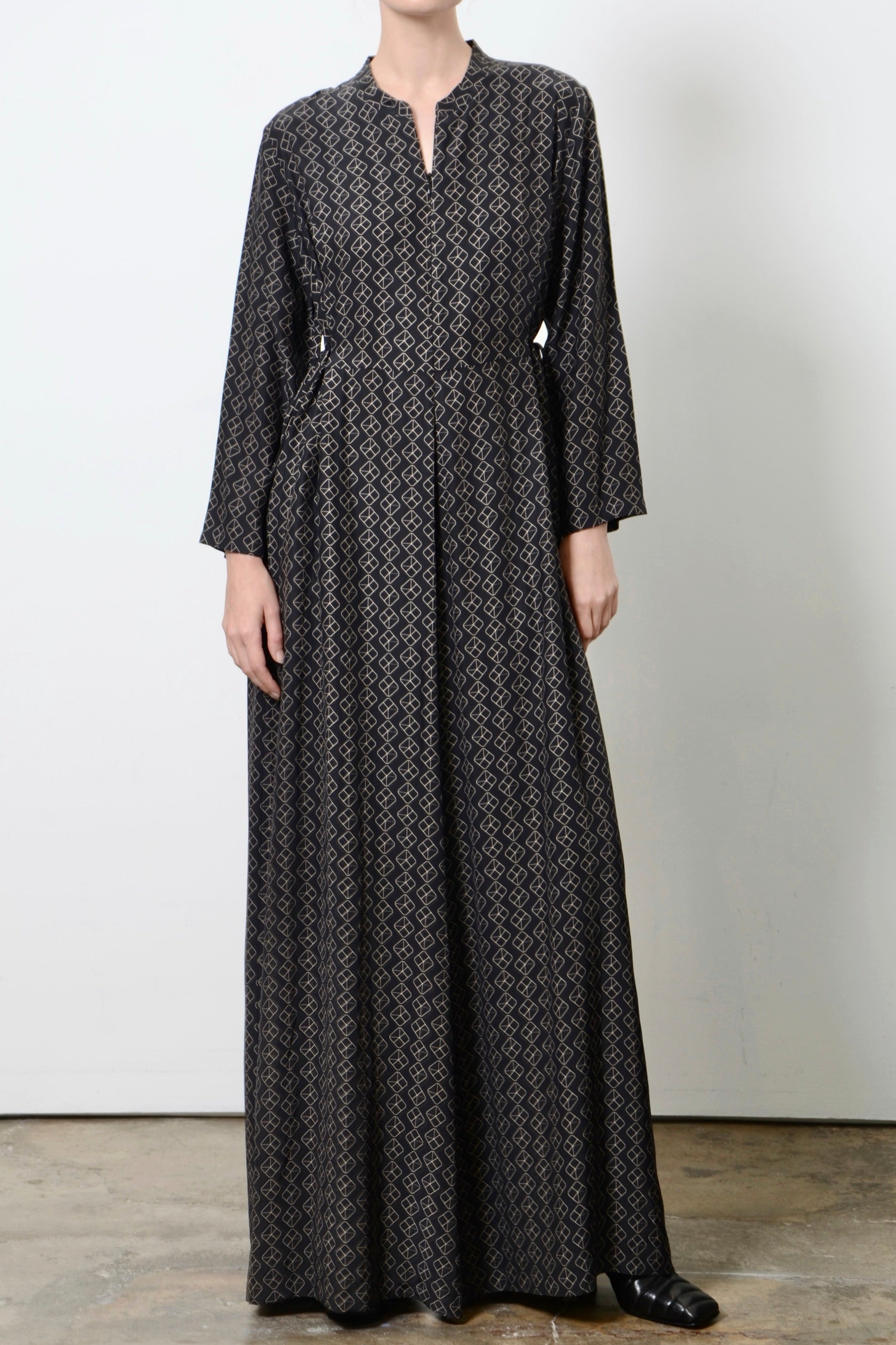 Long black patterned jumpsuit worn by a person on a white background