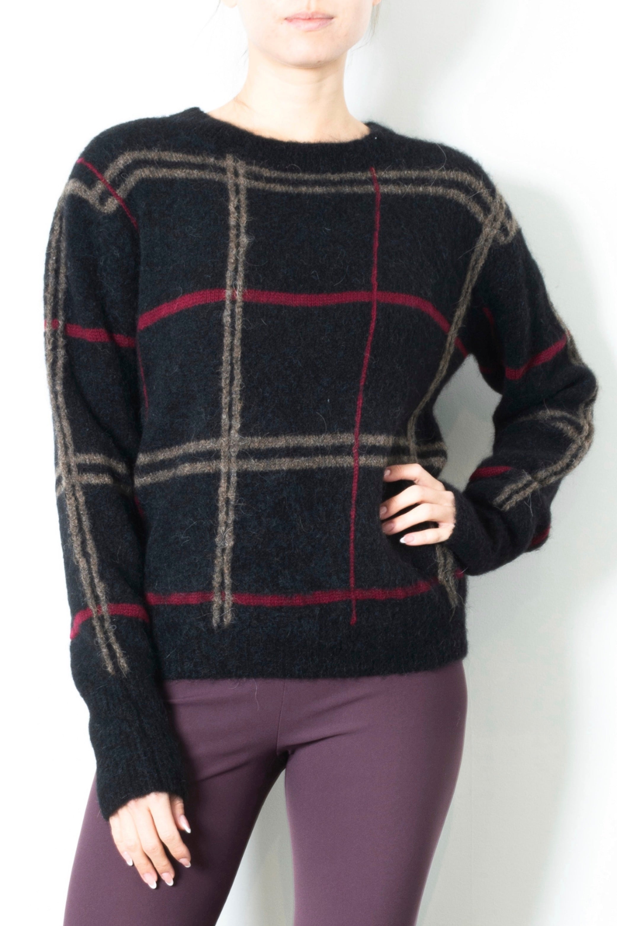 Person wearing a black sweater with plaid pattern on a white background