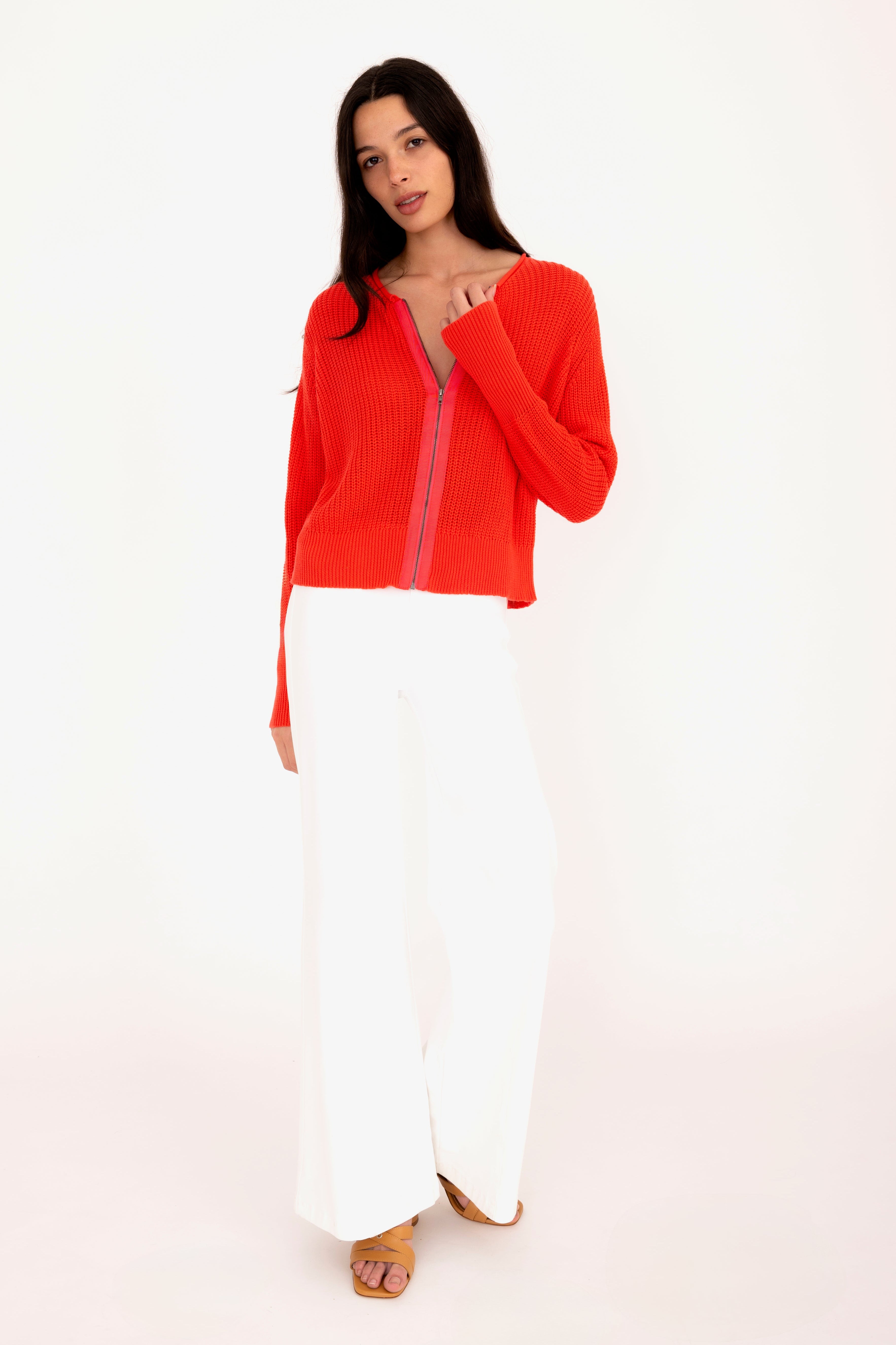 Woman wearing a red jacket and white pants on a white background