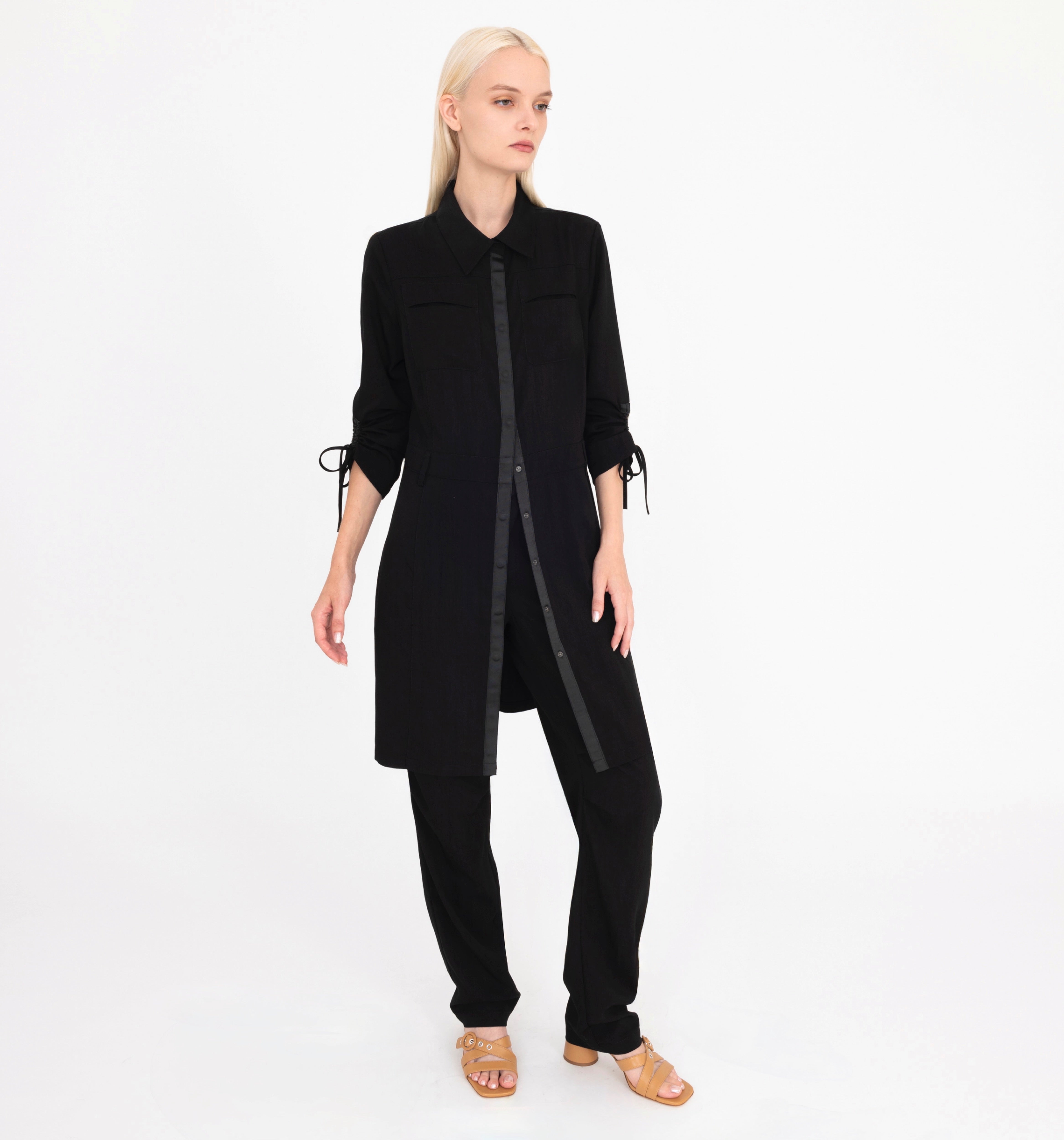 Woman wearing a black long top and pants on a white background