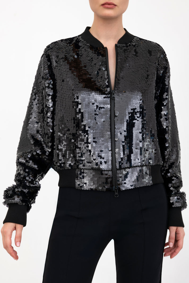 Black sequin bomber jacket worn by a model on a white background