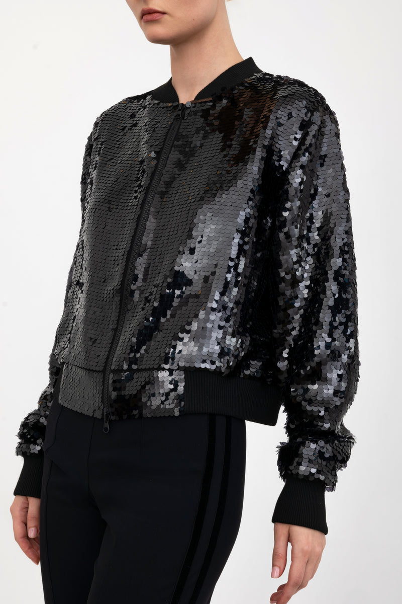 Black sequin bomber jacket worn by a model on a white background