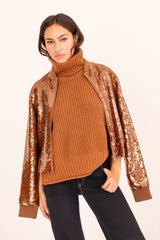 Woman wearing a brown ribbed sweater with sequin sleeves on a white background