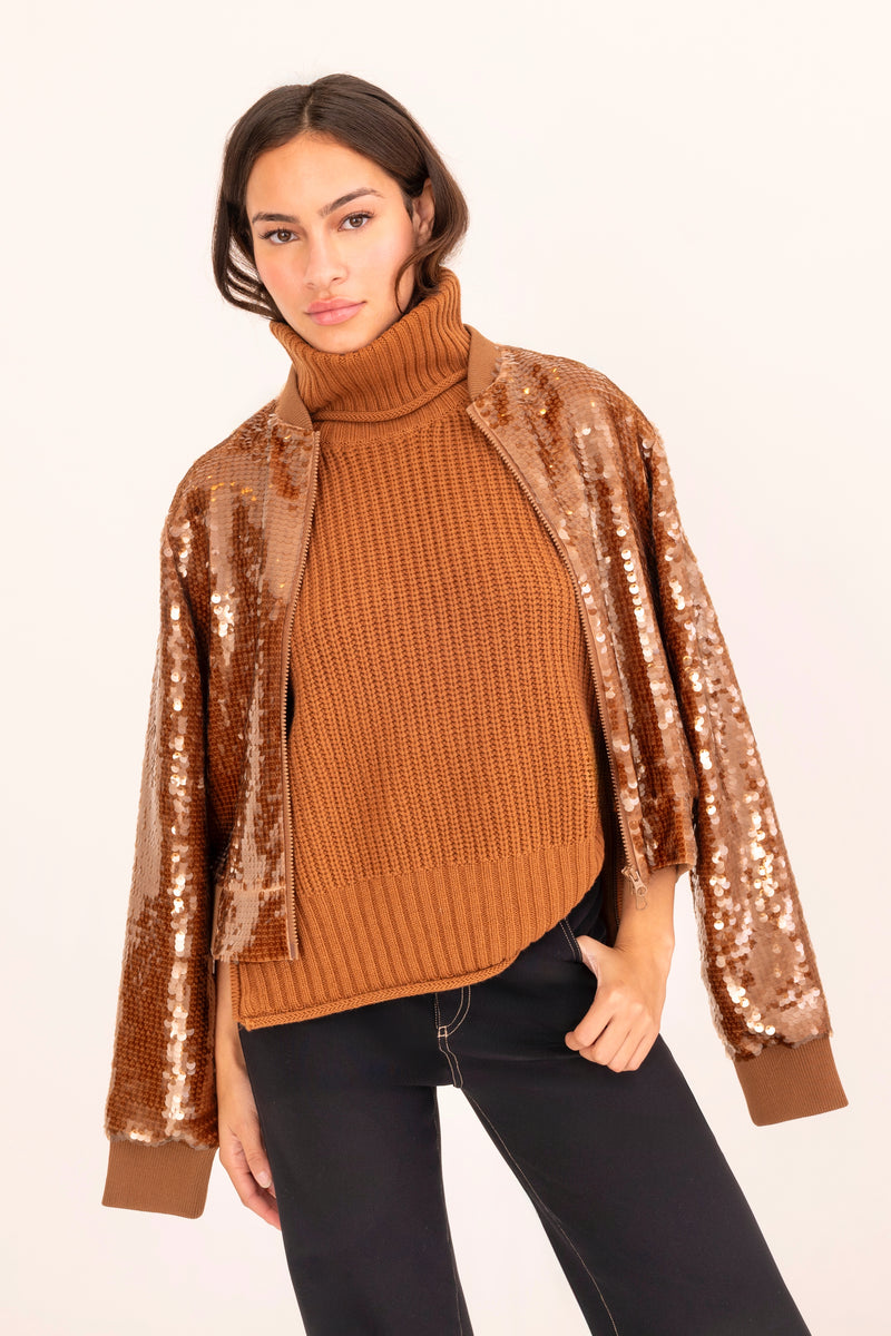 Woman wearing a brown ribbed sweater with sequin sleeves on a white background