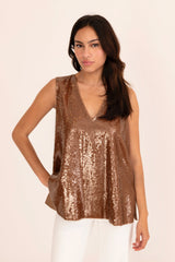 Woman wearing a bronze sequin top against a beige background