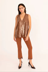 Woman wearing a brown sequin top and brown pants on a white background