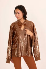 Woman wearing a bronze sequin jacket on a beige background