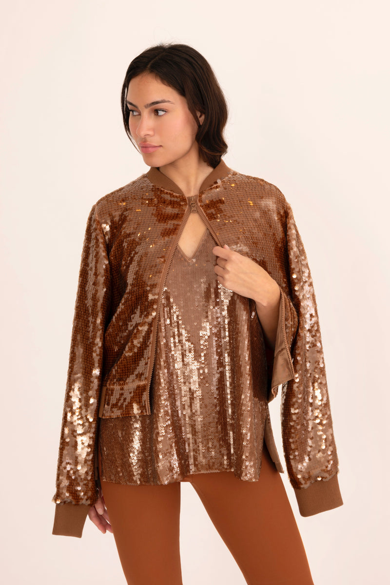 Woman wearing a bronze sequin jacket on a beige background