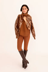 Woman wearing a brown outfit with a patterned jacket on a beige background