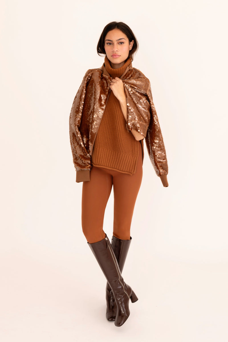 Woman wearing a brown outfit with a patterned jacket on a beige background