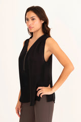 Woman wearing a black sleeveless top and brown pants on a white background