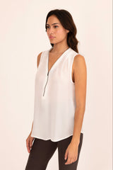 Woman wearing a white sleeveless top with a V-neckline on a beige background