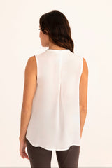 Woman wearing a white sleeveless top on a beige background