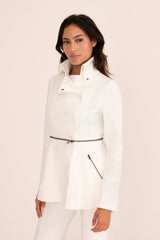 Woman wearing a white coat against a light pink background