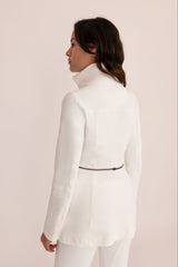 Woman wearing a white suit against a plain background