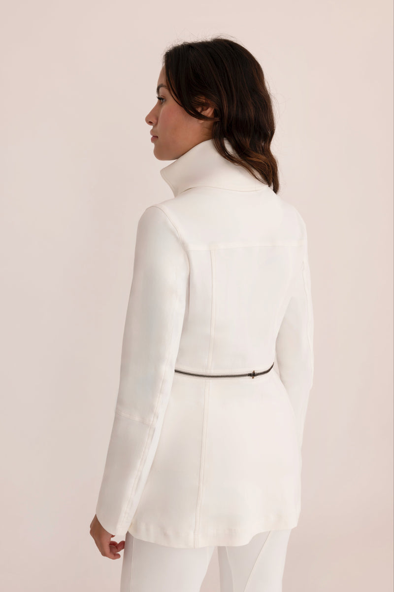 Woman wearing a white suit against a plain background