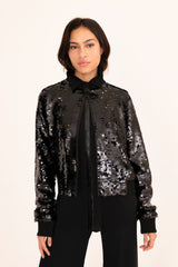 Woman wearing a black sequin jacket over a black shirt on a white background