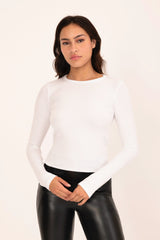 Woman wearing a white long-sleeve top and black leather pants on a beige background
