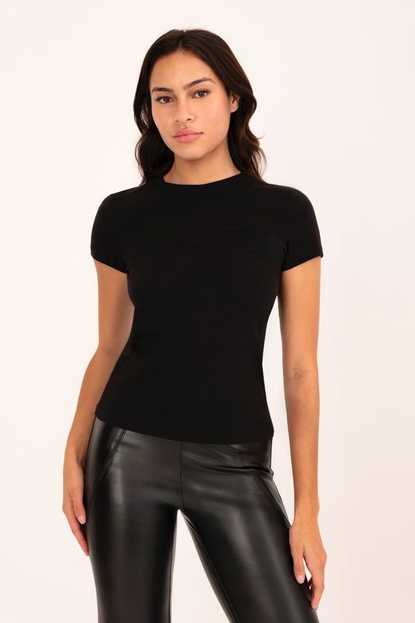 Woman wearing a black t-shirt and black leather pants on a white background