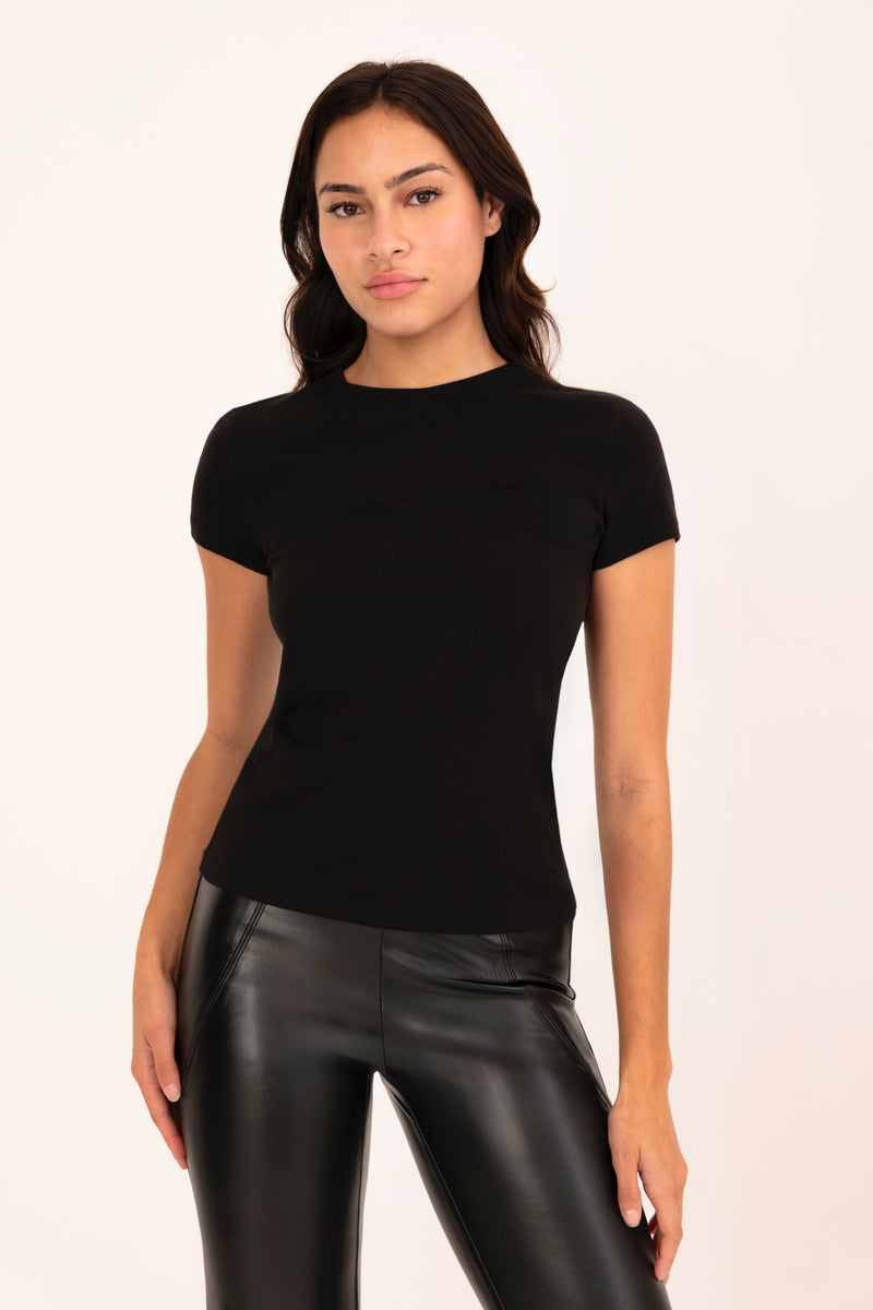 Woman wearing a black t-shirt and black leather pants on a white background