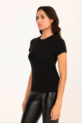 Woman wearing a black t-shirt and black leather pants on a white background