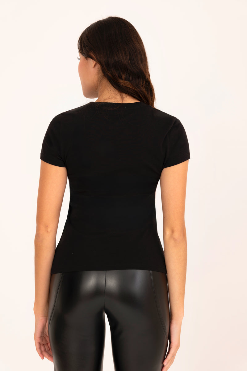 Woman wearing a black t-shirt and black leather pants on a white background