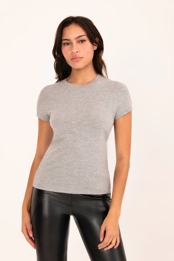 Woman wearing a gray t-shirt and black leather pants on a white background