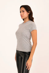 Woman wearing a gray t-shirt and black leather pants on a white background